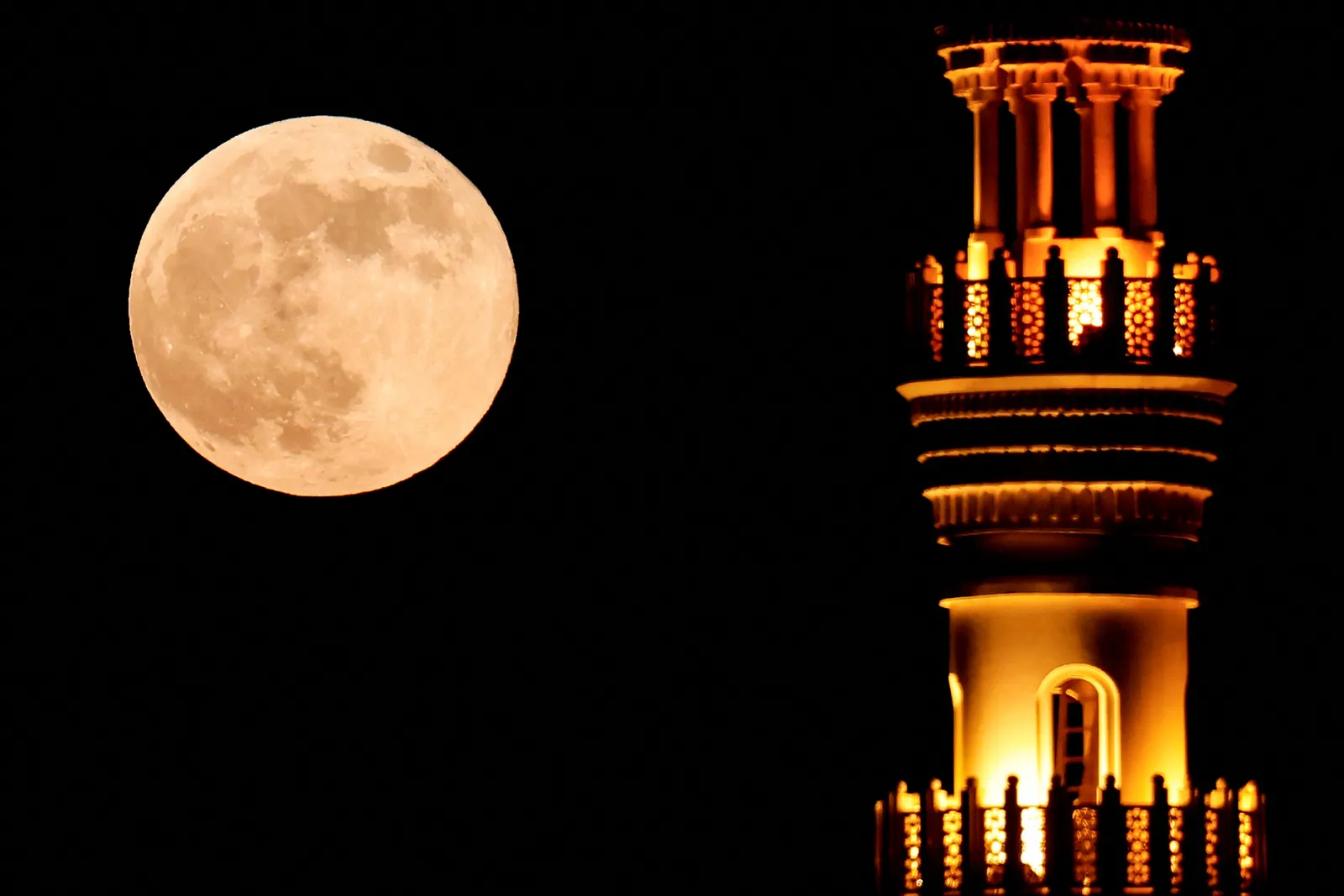 La luna llena del cazador se eleva tras el minarete de una mezquita en Doha el 17 de octubre de 2024